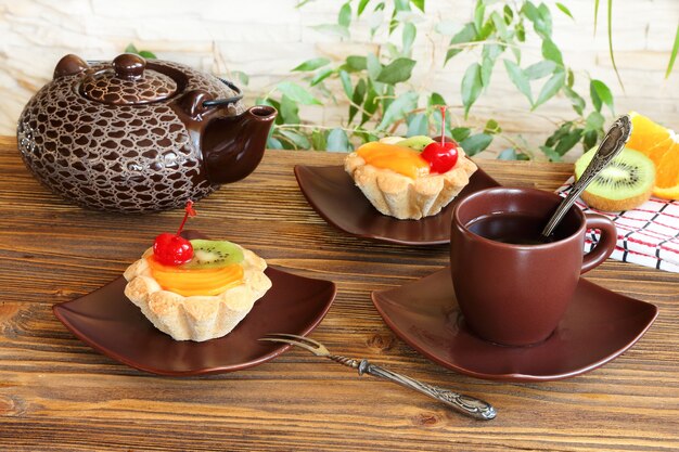 Tartelettes aux fruits et thé sur une table en bois