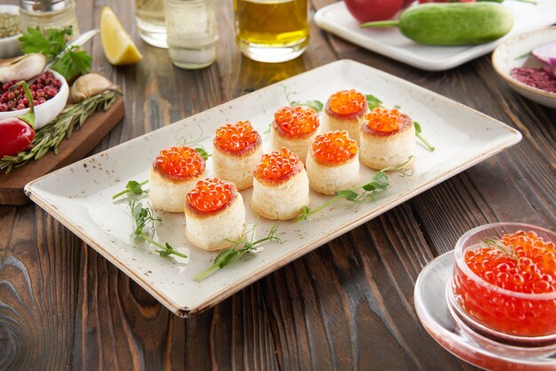 Tartelettes ou canape au caviar rouge et ingrédients sur table en bois, concept de cuisson