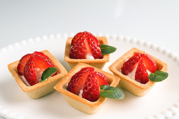 Tartelettes carrées aux fraises au yaourt et feuilles de menthe sur une assiette blanche