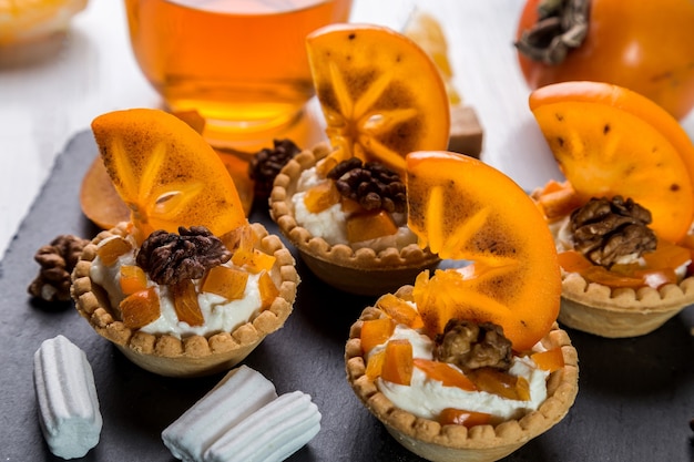 Tartelettes à la crème de caillé, kaki et thé dans une tasse transparente.