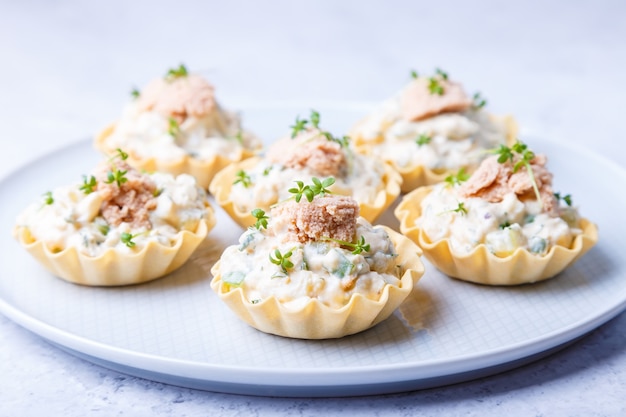 Tartelettes farcies au foie de morue, caviar de morue, concombre et micropousses. Apéritif traditionnel en portion froide dans un panier à pâtisserie. Fermer.