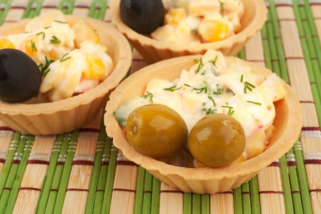 Tartelettes avec salade de crabe et olives. Tartelettes avec salade sur une serviette en bambou