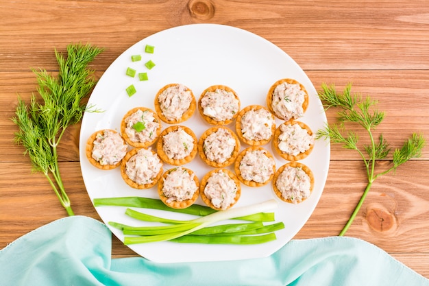 Des tartelettes avec une salade de sury et des œufs sont disposées sur une assiette en forme de poisson, vue de dessus