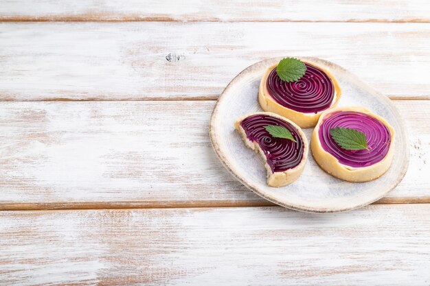 Tartelettes sucrées à la gelée et crème de lait sur un fond en bois blanc. Vue latérale, copiez l'espace.