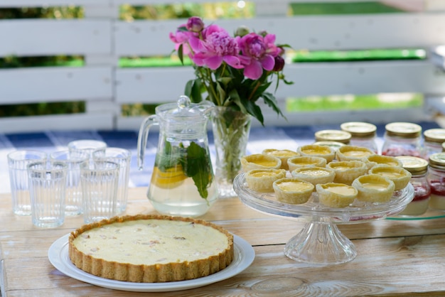 Des tartes appétissantes et de la limonade sont cuites sur une table de pique-nique en bois blanc avec un vase de fleurs de pivoine. Vacances d'été en famille. Pique-nique.