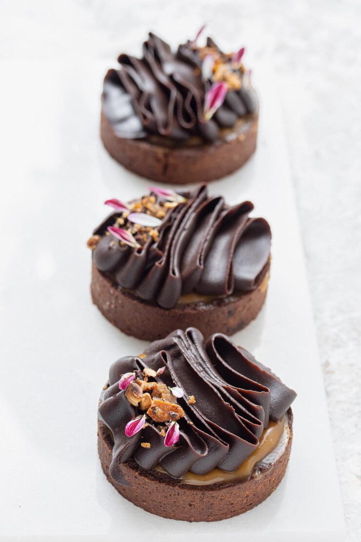 Photo des tartes au chocolat décorées de ganache au chocolat noir sur un fond blanc