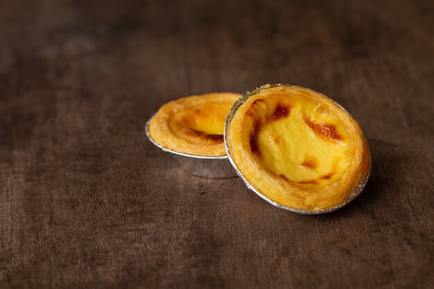 Tartes aux œufs dans une tasse en aluminium sur la table en bois, dessert portugais traditionnel servi dans un café