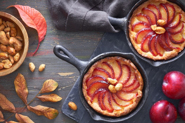 Tartes de crumble faites maison avec des tranches de prune cuites dans une petite poêle en fer.