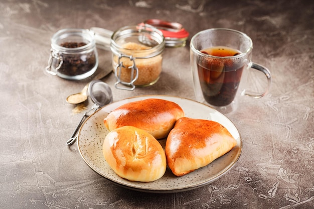 Tartes à la pâte à levure sucrée avec différentes garnitures sur plateau et verre de thé