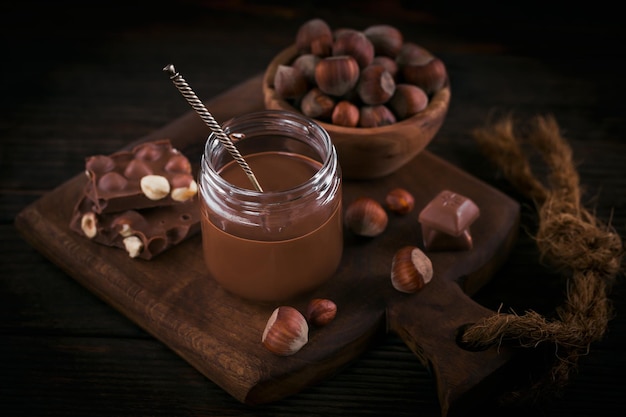 Tartinade de lait de noisette au chocolat fait maison sur un bocal en verre sur fond de bois foncé