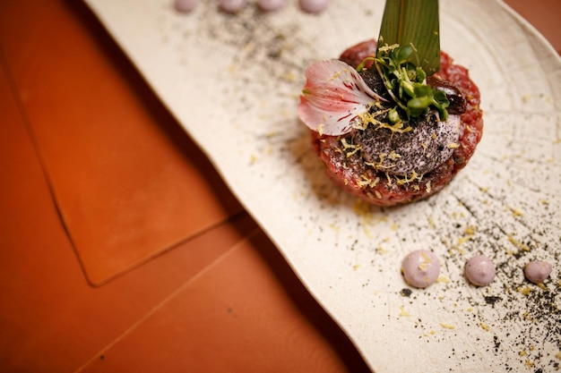 tartre sur une feuille verte sur une assiette blanche. tartare savoureux juteux avec sauce.