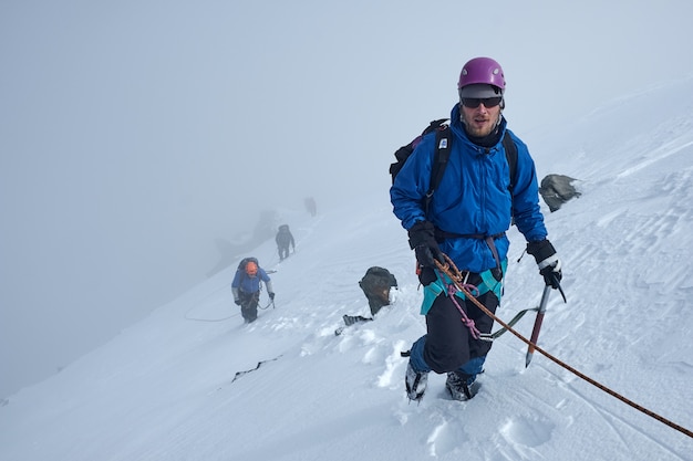 Un tas d'alpinistes grimpe ou alpinistes au sommet d'une montagne enneigée