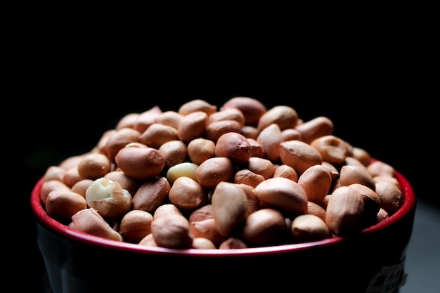 tas d'arachides ou de haricots épluchés dans un bol à fond noir