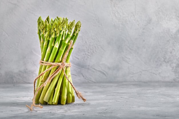 Tas d'asperges sur une table grise, espace copie, légumes biologiques frais, livraison de produits.