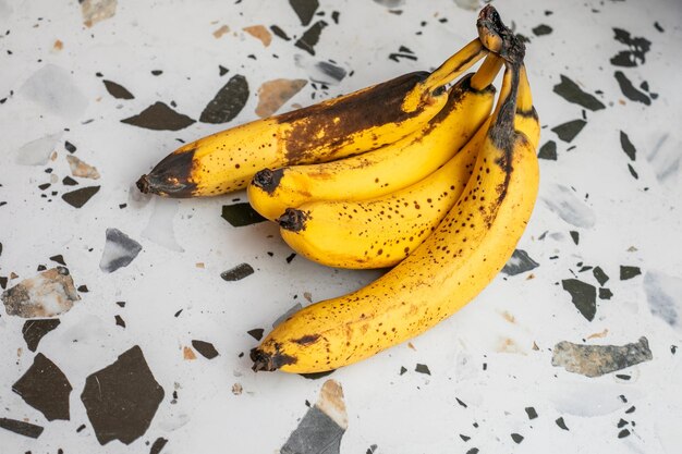 Un tas de bananes mûres avec des taches brunes sur un comptoir en terrazzo suggérant le concept de rip alimentaire