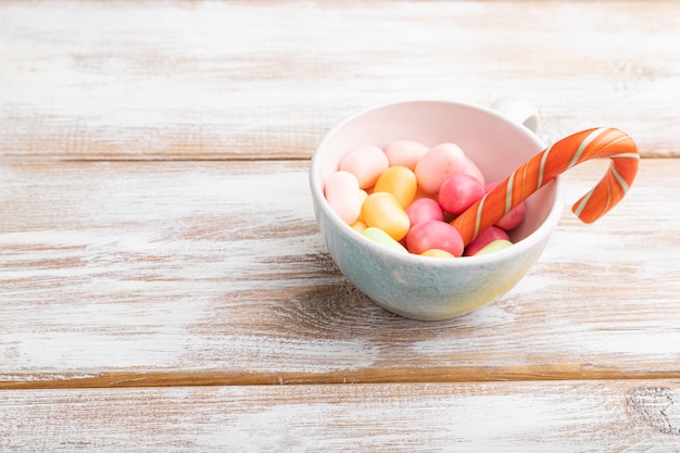 Tas de bonbons au caramel multicolores en tasse sur bois blanc