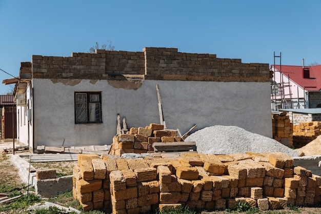 Un tas de briques se trouve devant la maison en construction