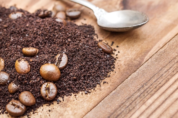 Tas de café moulu et de grains de café avec une cuillère sur la table