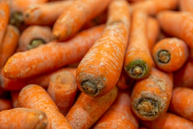 Un tas de carottes crues couchées les unes sur les autres. Couleur vive, longue et savoureuse, parfaite pour promouvoir un mode de vie sain et le végétarisme. Vue aérienne. Fermer.