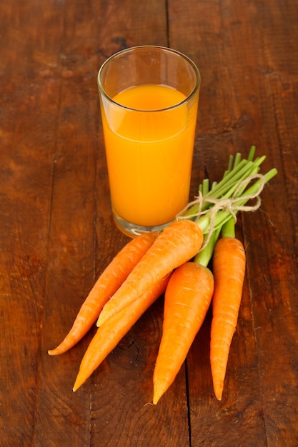 Tas de carottes verre de jus sur fond de bois