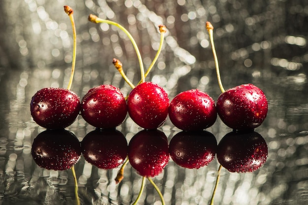 Tas de cerises avec des feuilles et des gouttes d'eau sur une table en pierre noire