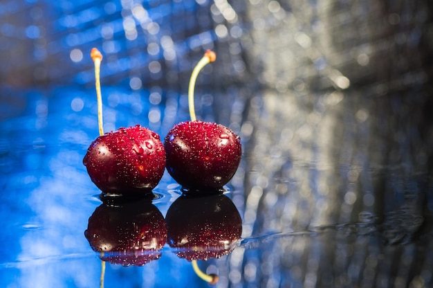 Tas de cerises avec des feuilles et des gouttes d'eau sur une table en pierre noire