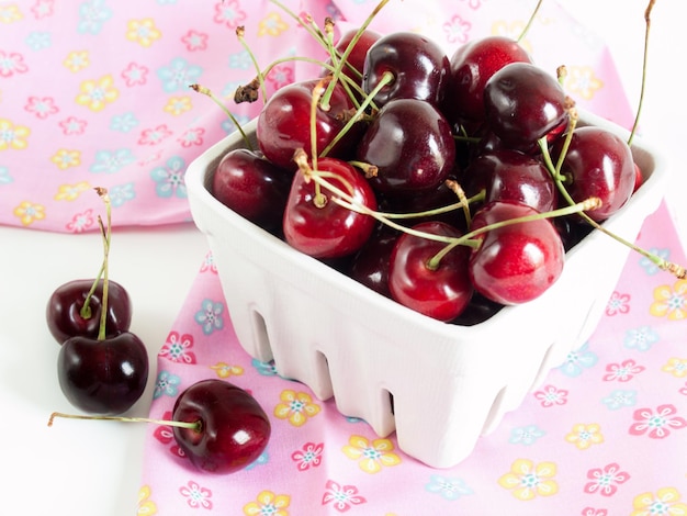 Photo tas de cerises fraîchement cueillies dans un panier blanc.