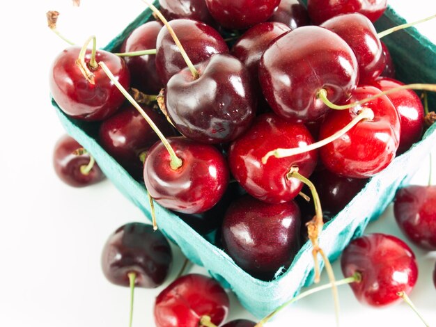 Photo tas de cerises fraîchement cueillies dans un panier bleu.