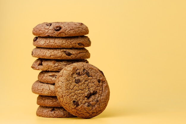 Tas de cookies aux pépites de chocolat sur fond jaune