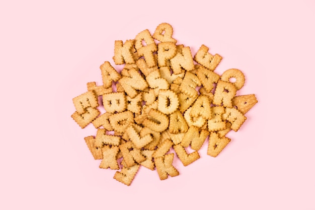 Un tas de cookies de lettres de l'alphabet sur fond rose