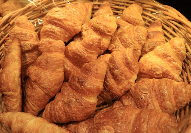 Tas de croissants aux amandes fraîchement cuites dans un panier, pour le fond