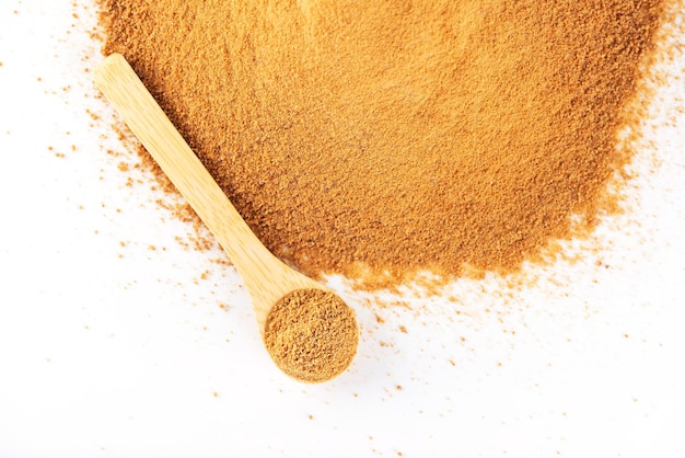 Tas avec cuillère en bois avec du sucre de canne non raffiné Panela sur fond blanc