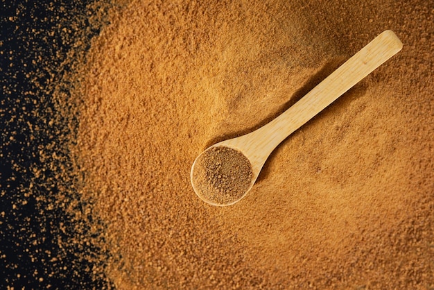 Tas avec une cuillère en bois avec du sucre de canne non raffiné Panela sur fond noir