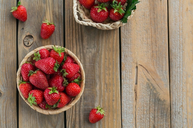 Tas de fraises fraîches dans un panier sur fond de bois rustique. Concept d'alimentation saine et diététique. Aérien