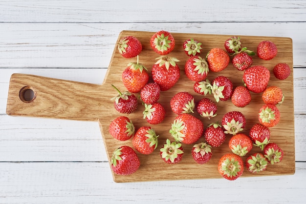 Tas de fraises fraîches avec planche à découper