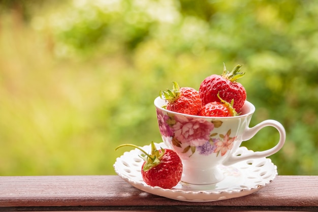 Un tas de fraises de jus de fruits mûrs dans une tasse sur une table en bois.Des fraises fraîches sur le marché des fermiers.Une nourriture saine pour le petit déjeuner et une collation.Espace copie