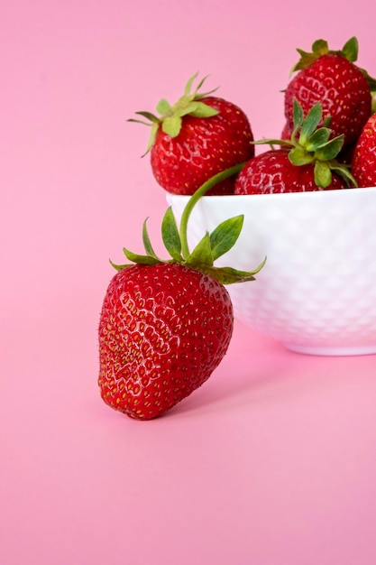 Tas de fraises juteuses dans un bol en céramique sur fond rose Une saine alimentation aux fruits et un concept alimentaire détox Close up fresh farm berry
