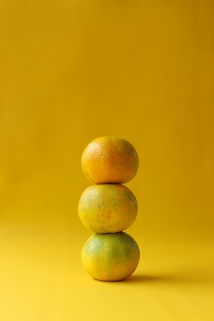 Tas de fruits orange disposés sur fond jaune Copiez l'espace pour la production agricole et des aliments sains