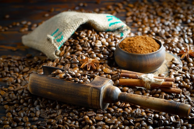 Un tas de grains de café avec de la cannelle sur le dessus et une cuillère en bois avec de la cannelle sur le dessus.