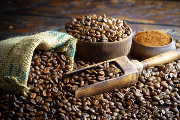 Un tas de grains de café avec une cuillère en bois à côté.