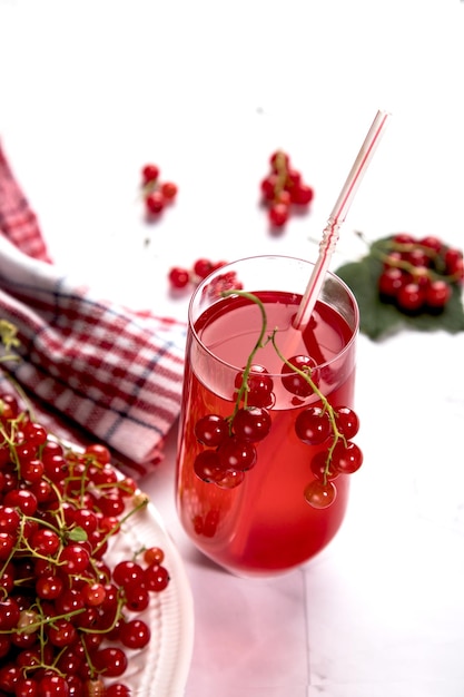 Un tas de groseilles rouges sur un verre de jus de fruits