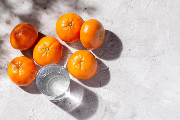 Tas de mandarines fraîches et de verre avec de l'eau sur la table en béton