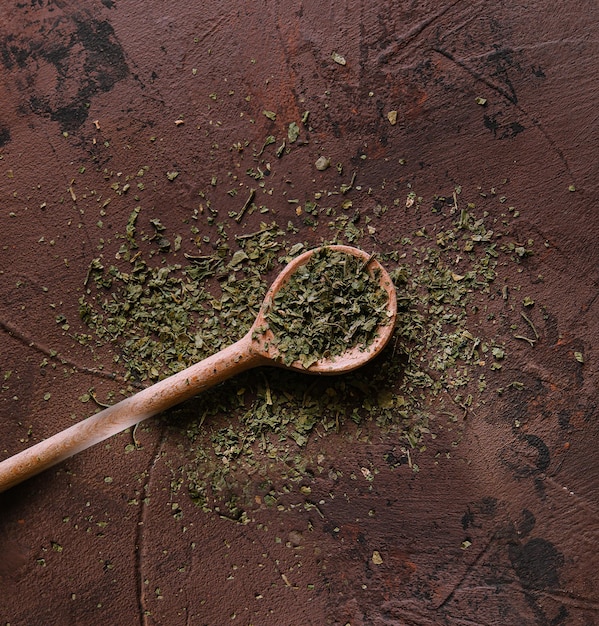 Un tas de mélange d'épices vertes, de légumes séchés et d'herbes sur une cuillère en bois