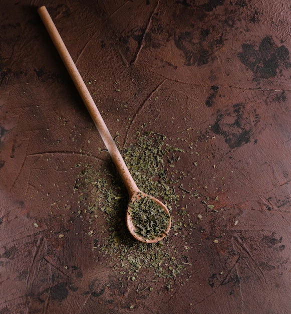 Photo un tas d'un mélange d'épices vertes de légumes séchés et d'herbes sur une cuillère en bois