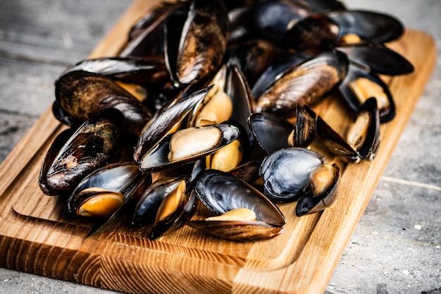 Un tas de moules bouillies sur une planche à découper en bois