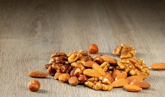 Un tas de noix, noisettes, noix et amandes sur une table en boisGros plan