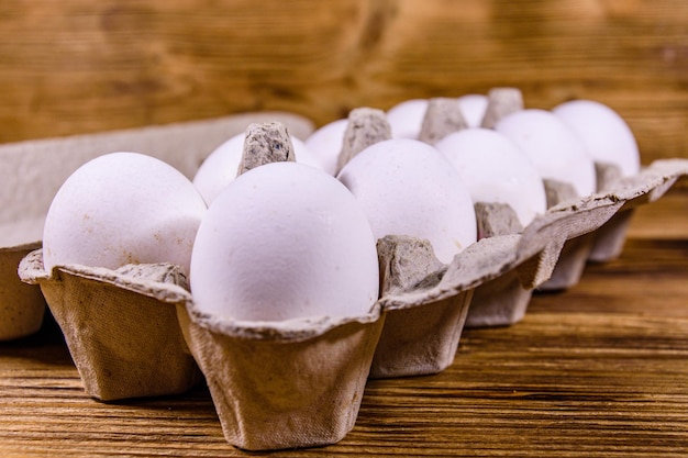 Tas d'oeufs de poule dans un bac à papier sur une table en bois