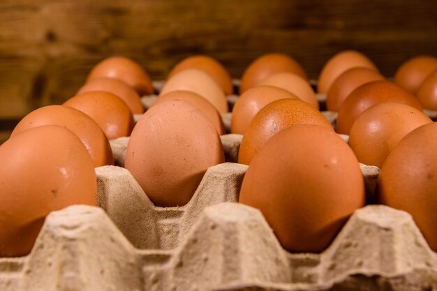 Tas d'oeufs de poule dans un bac à papier sur une table en bois