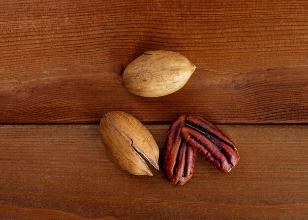 Tas de pacanes en coque et décortiqué décortiqué écrou décortiqué sur table en bois. Vue de dessus