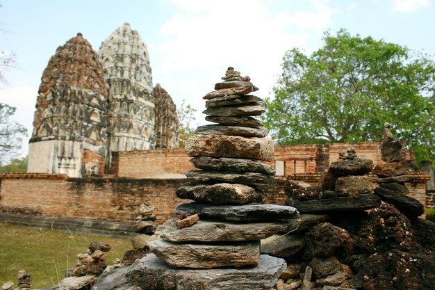 Un tas de pierres devant un temple avec un grand bâtiment en arrière-plan.